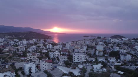 Aerial-view-of-Ksamil-waterfront-village,-during-scenic-Sunset-seascape,-Albania