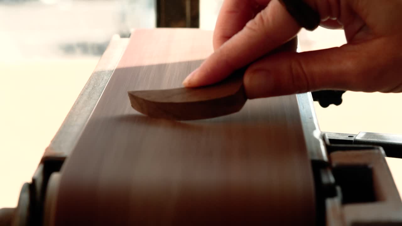 mujer de cerca lijando una pieza de arte de madera en una lijadora de banda carpintería 4k a cámara lenta 60 fps