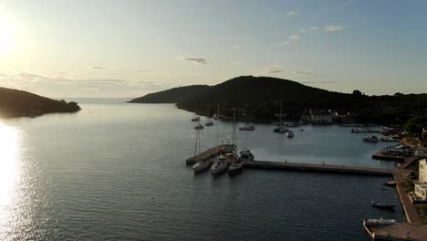 Una-Toma-De-Drone-De-Un-Pequeño-Puerto-Donde-Hay-Un-Par-De-Veleros-Atracados-En-Un-Muelle-De-Piedra