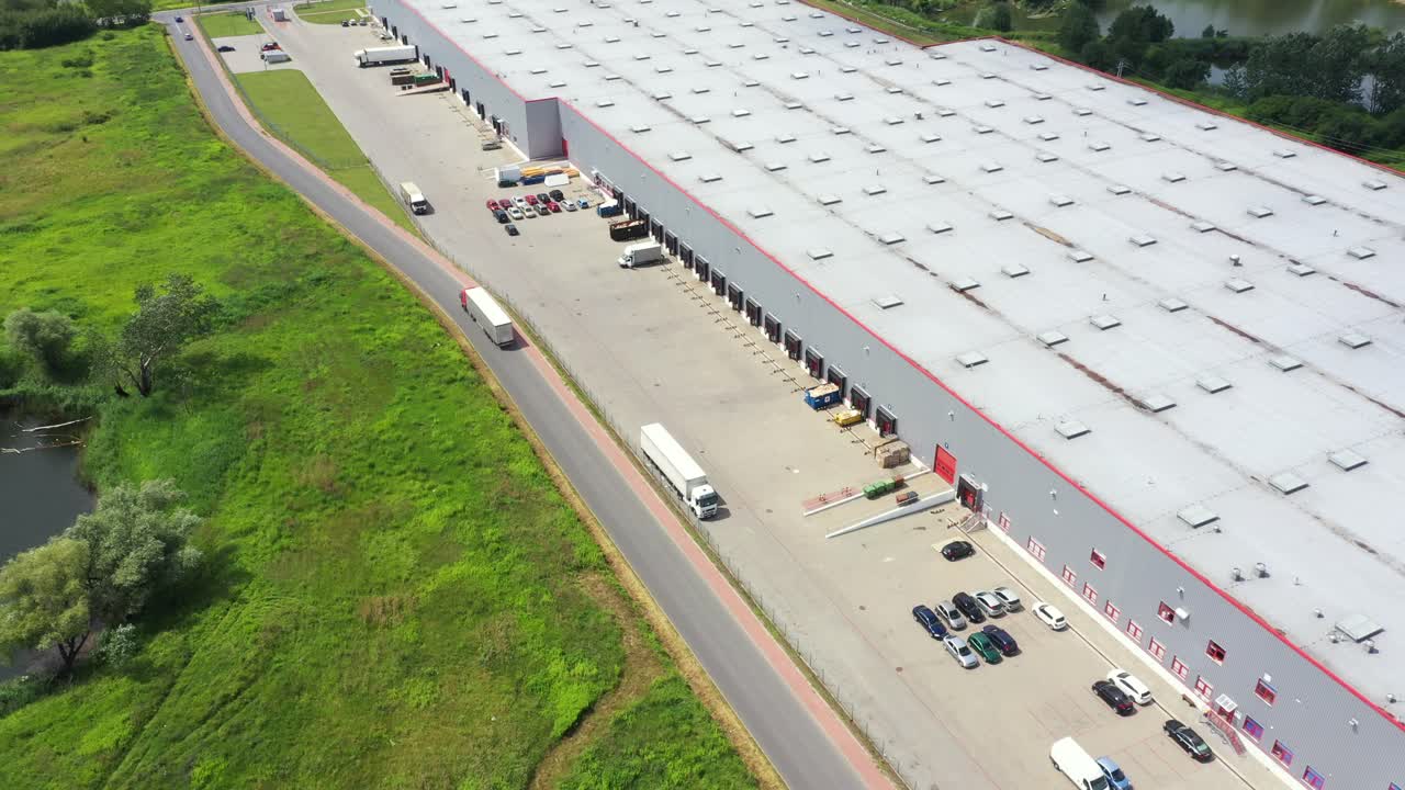 Bygninger til logistikcenter, varehuse nær motorvejen, parkering af lastbiler, udsigt fra højden, et stort antal lastbiler på parkeringspladsen nær varehuset