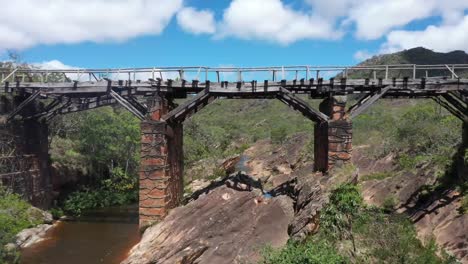 Vista-Aérea-De-Drones-De-Un-Viejo-Puente-Con-Un-Río-Marrón-Que-Fluye-Debajo-1