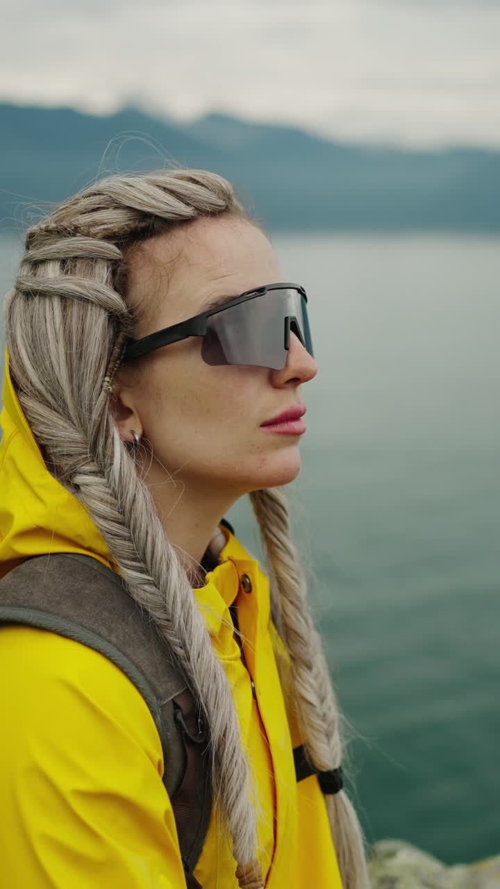 Thoughtful Woman in Yellow Raincoat Gazing at Lake