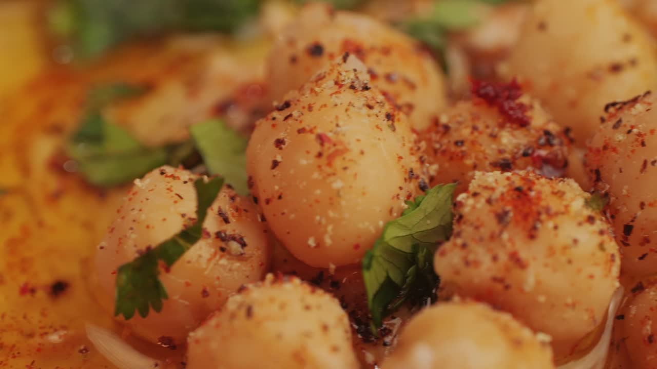 Hummus among fresh vegetables on table close-up. Hummus garnished with chickpeas, olive oil, spices and greens. Hummus or fava, a hearty snack of legumes. Kosher healthy vegan food. Lean, vegetarian dish