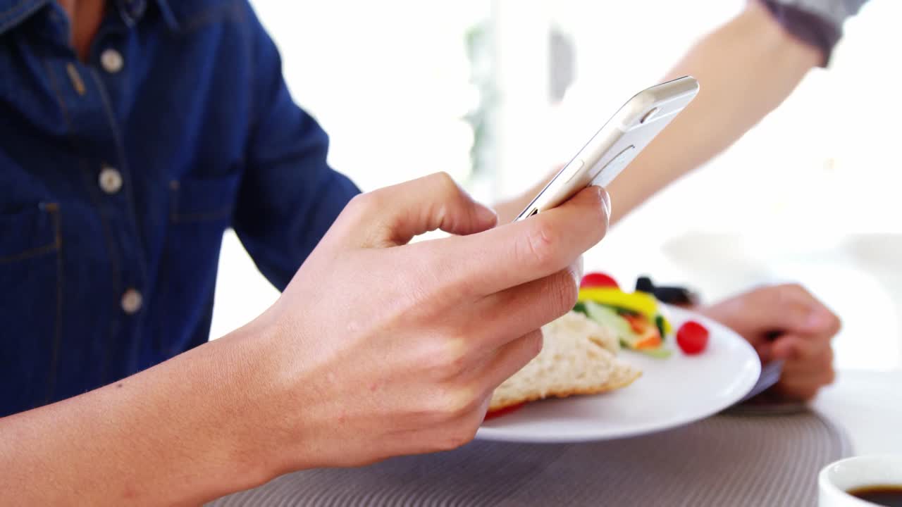 un hombre de negocios enviando mensajes de texto y esperando su almuerzo.