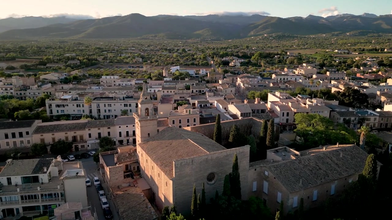 Volo di drone sul paesaggio di case tradizionali di Santa Maria del Camí, Maiorca, con sfondo montano al tramonto spagnolo