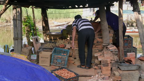 rear view of southeast asia potters by riverside placing clay figurines into crate, than ha hoi an vietnam