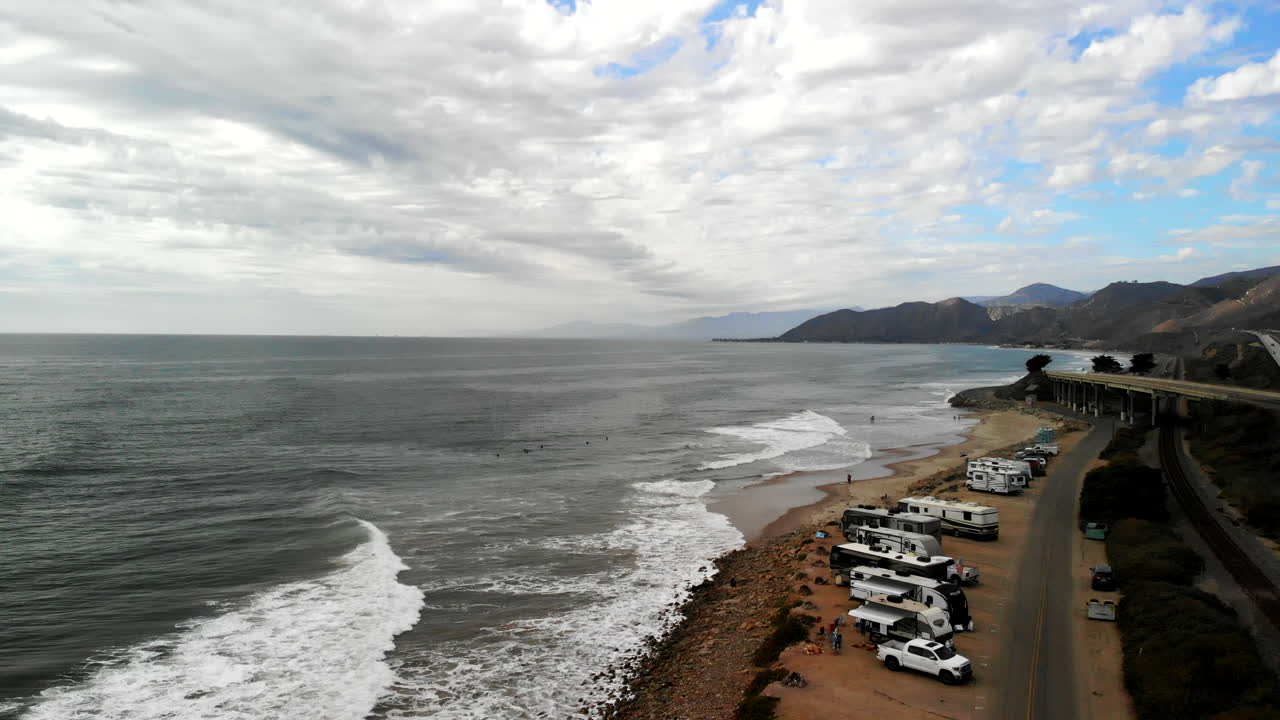 해안을 따라 분주한 캘리포니아 101 고속도로 옆에 있는 서퍼와 캠핑카와 함께 벤츄라의 주립 해변에서 공중 드론 촬영