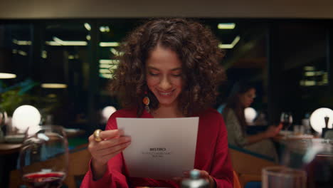 pretty african american woman choosing looking menu at fancy restaurant table.