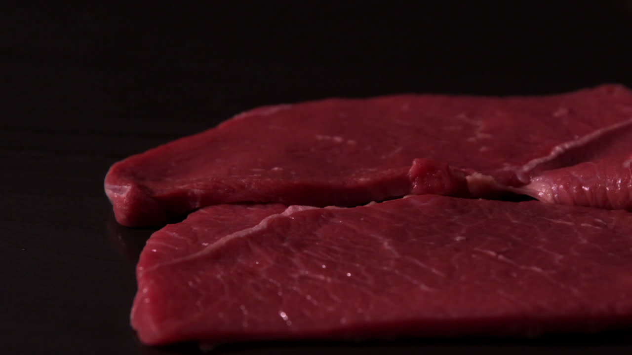 Beef steaks falling on black background