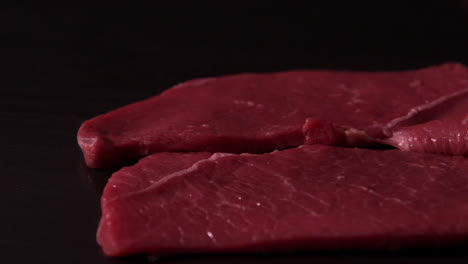 los filetes de carne caen sobre un fondo negro