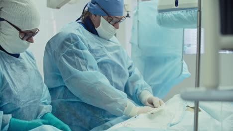 male and female surgeon in blue gown operating in an operating room