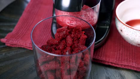 close up of beets being juiced and beet pulp falling out inside of a container making dessert beet muffin