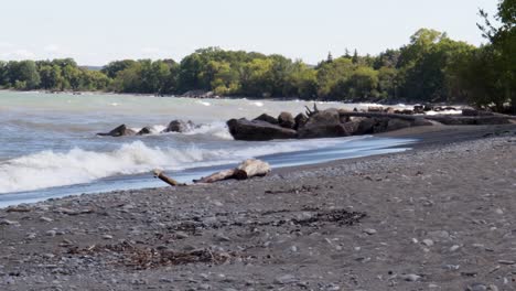 waves gently crashing along a rocky shoreline, from left to right, with lots of beach visible