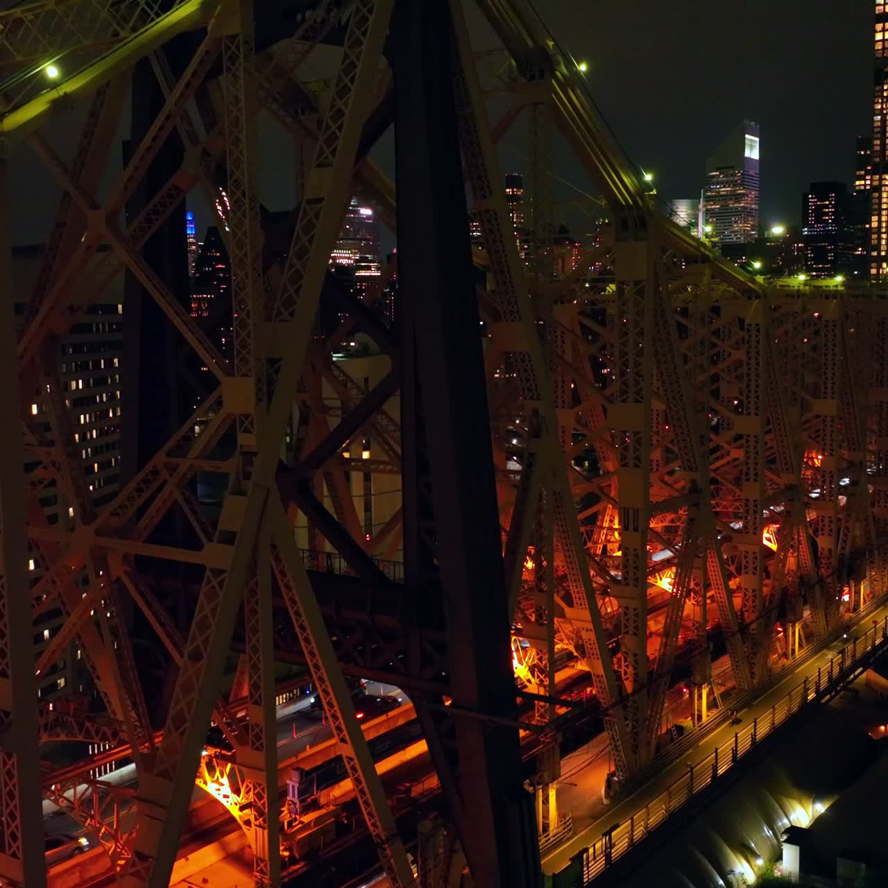 Terrific Queensboro Bridge with busy traffic at nighttime. Drone footage up along the bridge. New York skyline at backdrop