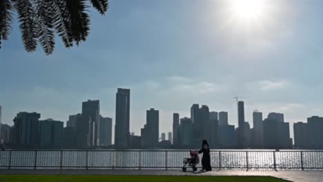 Slow-motion,-Out-of-focus:-Arab-mother-having-a-walk-along-with-her-baby-in-the-stroller-at-Khalid-Lake-in-Sharjah,-United-Arab-Emirates
