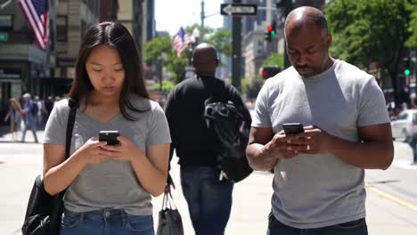 a young woman and middle-aged man engrossed in their smartphones while walking on a city sidewalk, capturing the essence of modern connectivity and urban life.