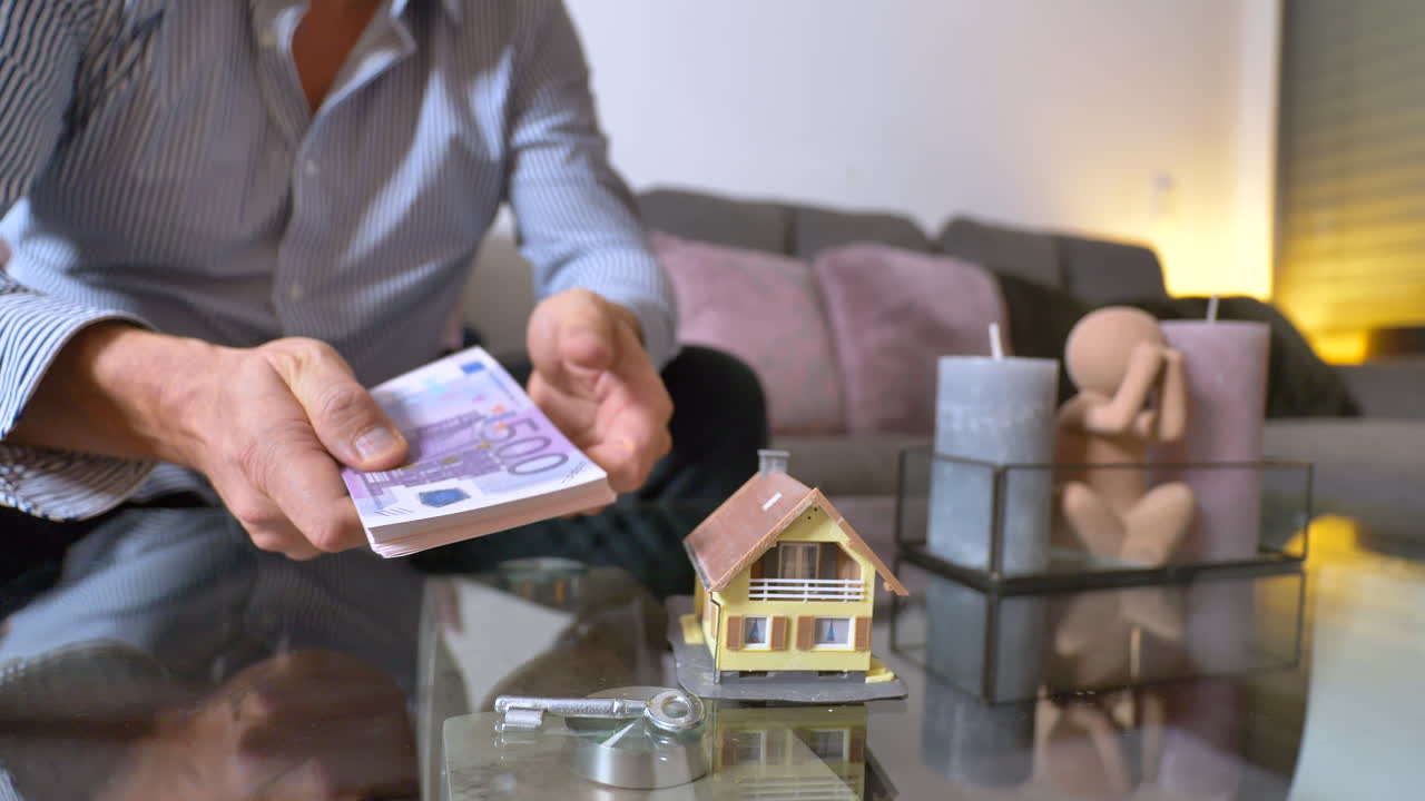 Uomo d'affari che conta banconote da 500 euro e prende la chiave di casa - Decisione tra denaro contante o proprietà di una villa - primo piano