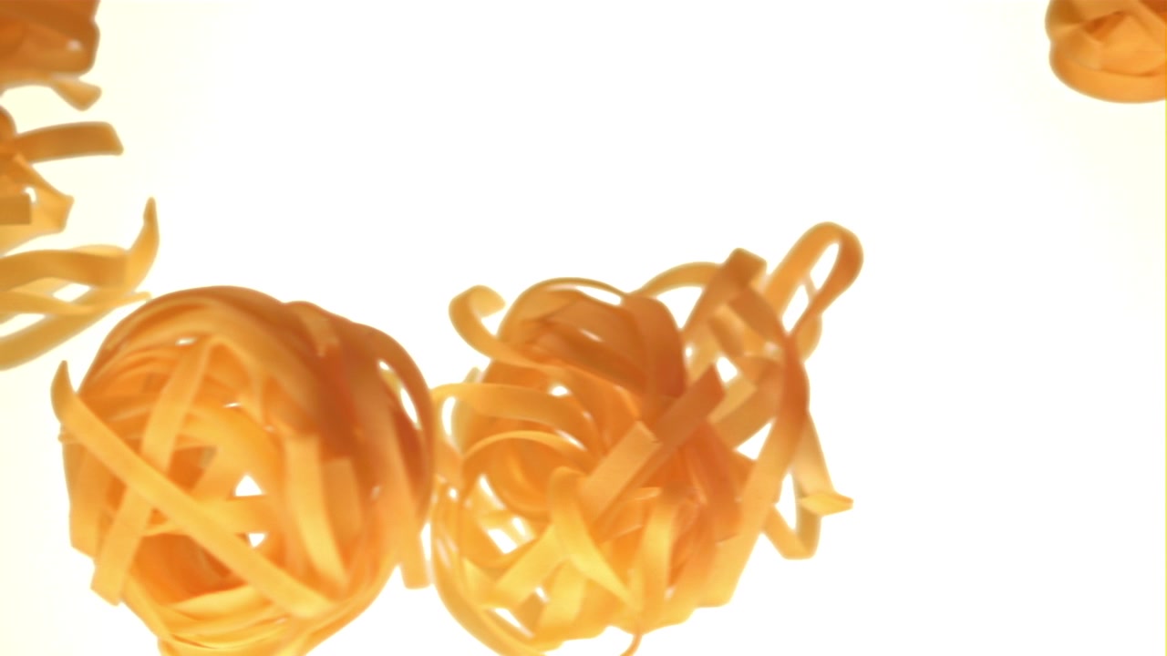 Tagliatelle crude che galleggiano verso l'alto su sfondo bianco