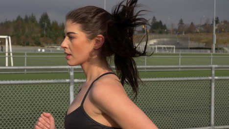 girl in revealing sportswear runs on the track, slow motion tracking