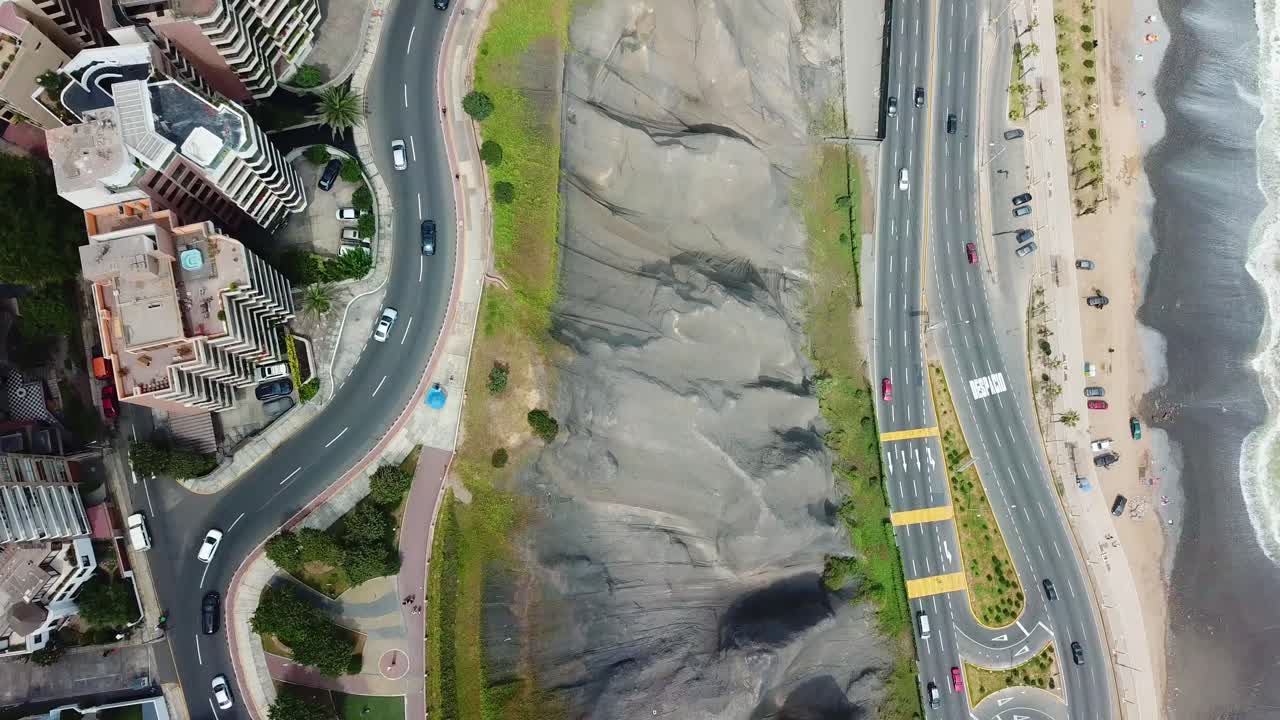 Aerial, rising, drone shot top down over traffic on Circuito de Playas road and the coastline of Lima city, Peru