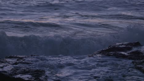 Close-up: Ocean spray crashes down on rocky tide pool. Filmed at sunset on the Oregon Coast.