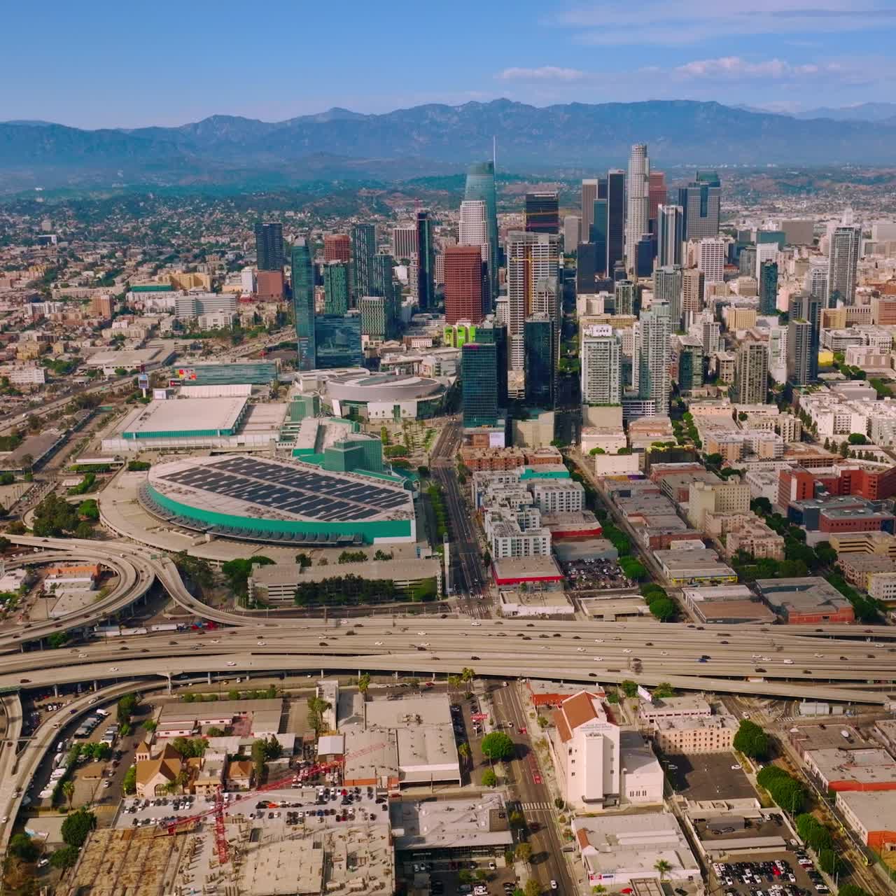 Numerous roads going round the financial downtown in Los Angeles, California. Sunny panorama at backdrop of beautiful hills. Aerial view