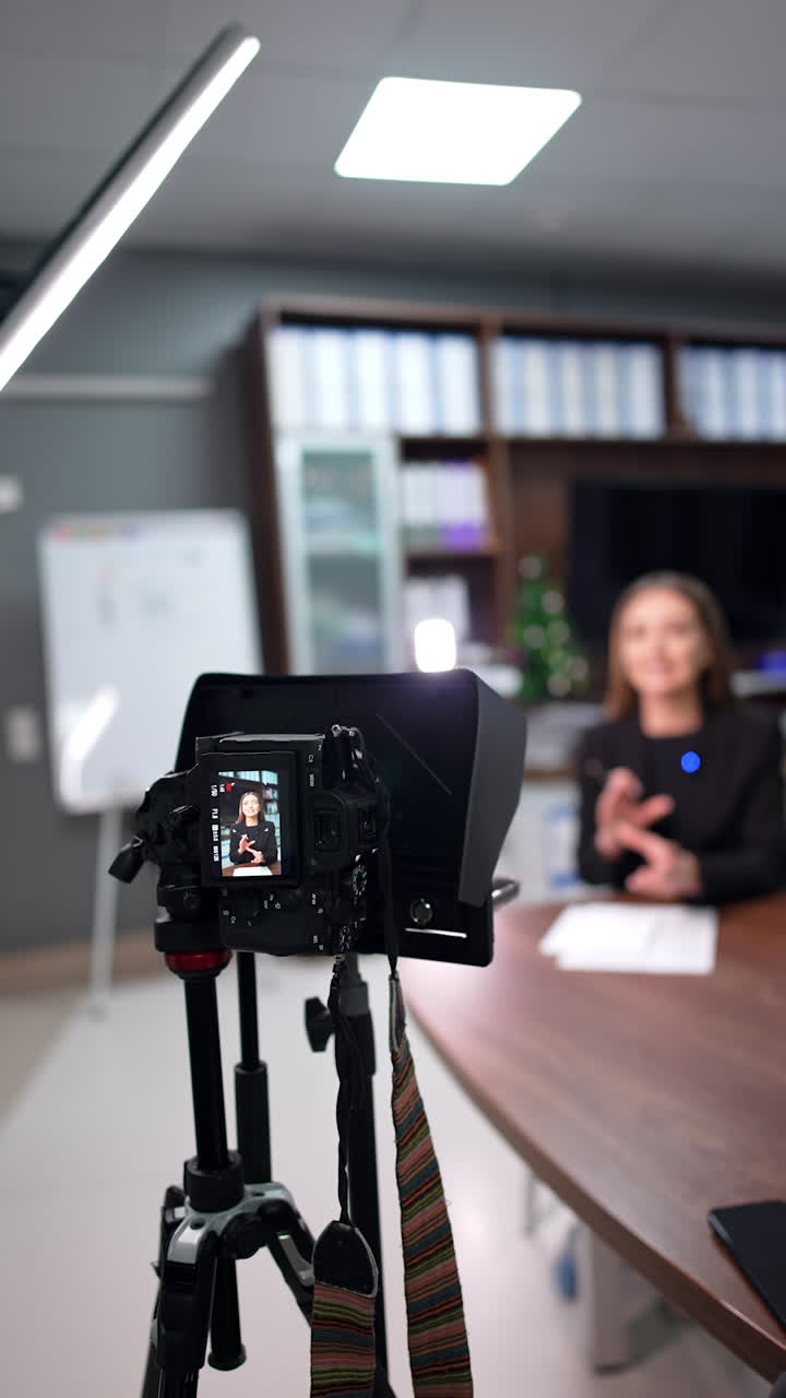 Footage of a blog on professional equipment. Camera on tripod records video content for female blogger. Blurred backdrop. Vertical video.