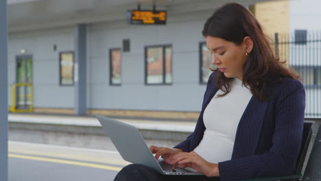 mujer de negocios viajando al trabajo esperando el tren en la plataforma de la estación trabajando en una computadora portátil