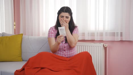 Woman-leaning-on-heater-looking-at-high-bill.