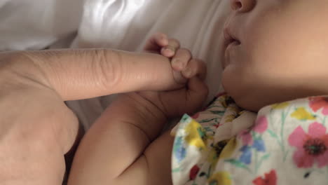 niña bebé sosteniendo el dedo de los padres