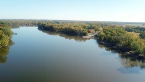 Niedriger-Winkel,-Langsamer-Drohnenblick-Auf-Den-Fluss-Iowa-Und-Den-Flusspfad,-Der-Sich-An-Einem-Sonnigen-Spätsommertag-In-Richtung-Einer-Bootsrampe-Und-Eines-Campingplatzes-Bewegt