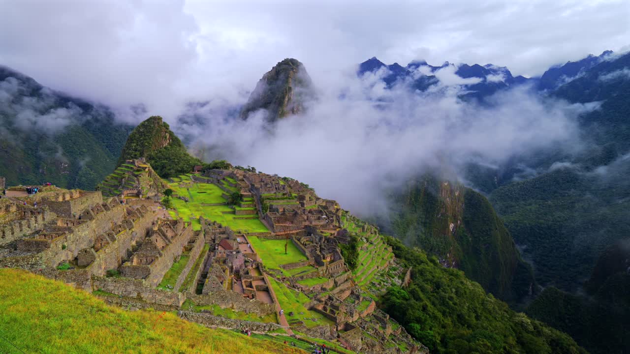 Paisagem de Machu Picchu, Peru, com o Templo da Trilha Inca, sob uma camada de neblina de nuvens baixas no início da manhã. O Circuito da Montanha Huayna Picchu e o santuário Patrimônio Mundial, com vista para Águas Calientes e as Montanhas Andinas Peruanas, em uma panorâmica para a esquerda.