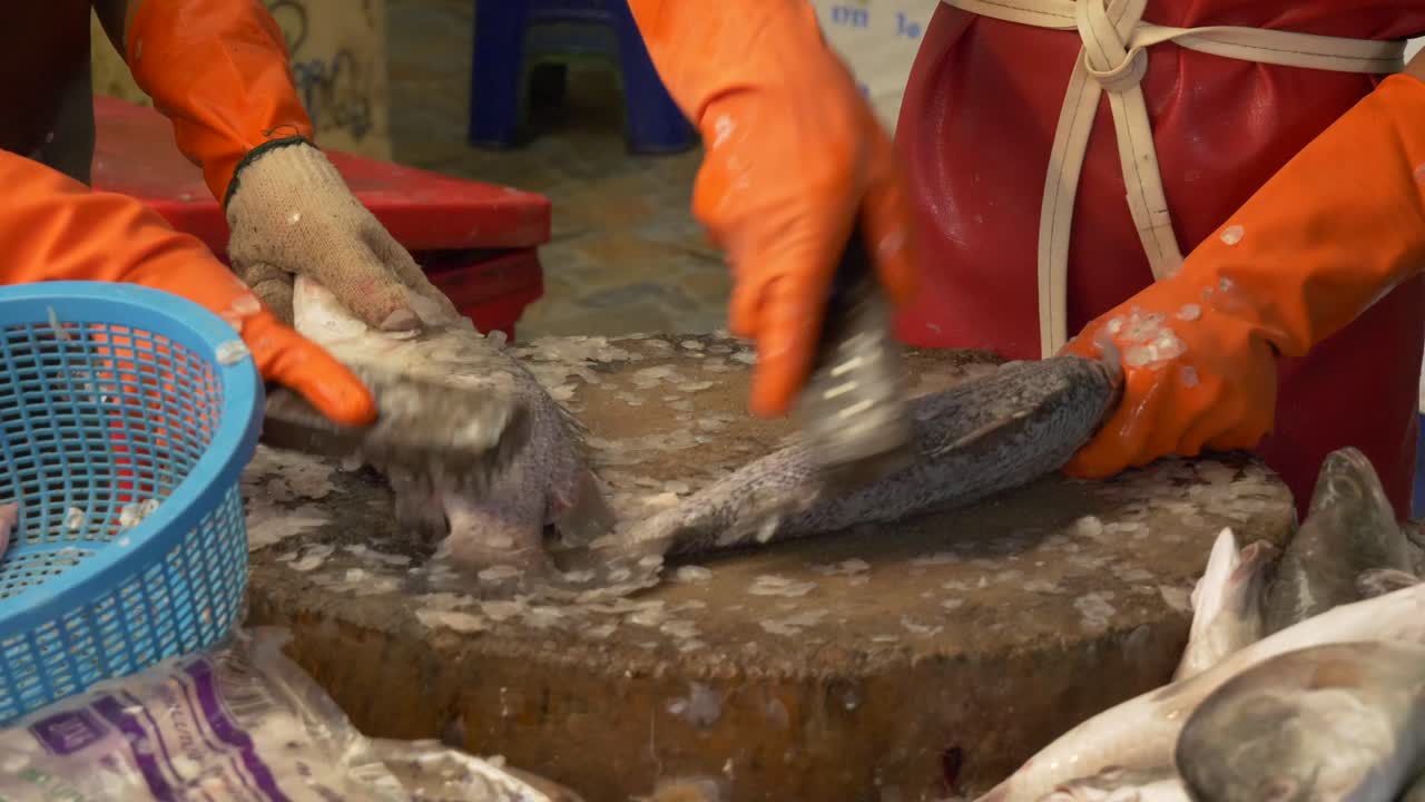 trabajador del mercado de pescado de la calle asiática de tailandia raspando escamas de pescado