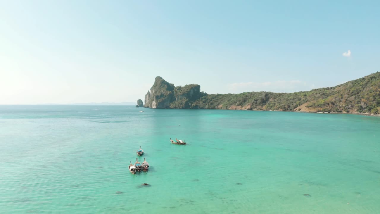 Breathtakingly beautiful Loh Dalum Bay, with Long-tail boats moored above Turquoise clear sea, Thailand - Aerial slide fly-over