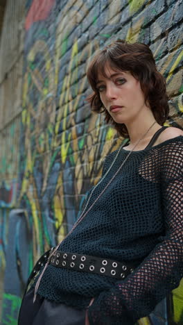 Vertical-Video-Outdoor-Fashion-Portrait-Of-Young-Alternative-Style-Woman-Leaning-Against-Graffitti-Covered-Wall-In-London-City-Street-UK-In-Real-Time-2