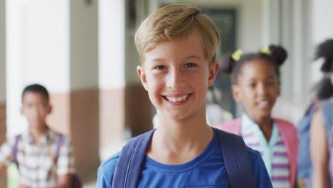 video of happy caucasian boy standing at school corridor