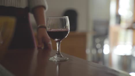 close up of female pouring red wine in a glass inside home or restaurant cafe