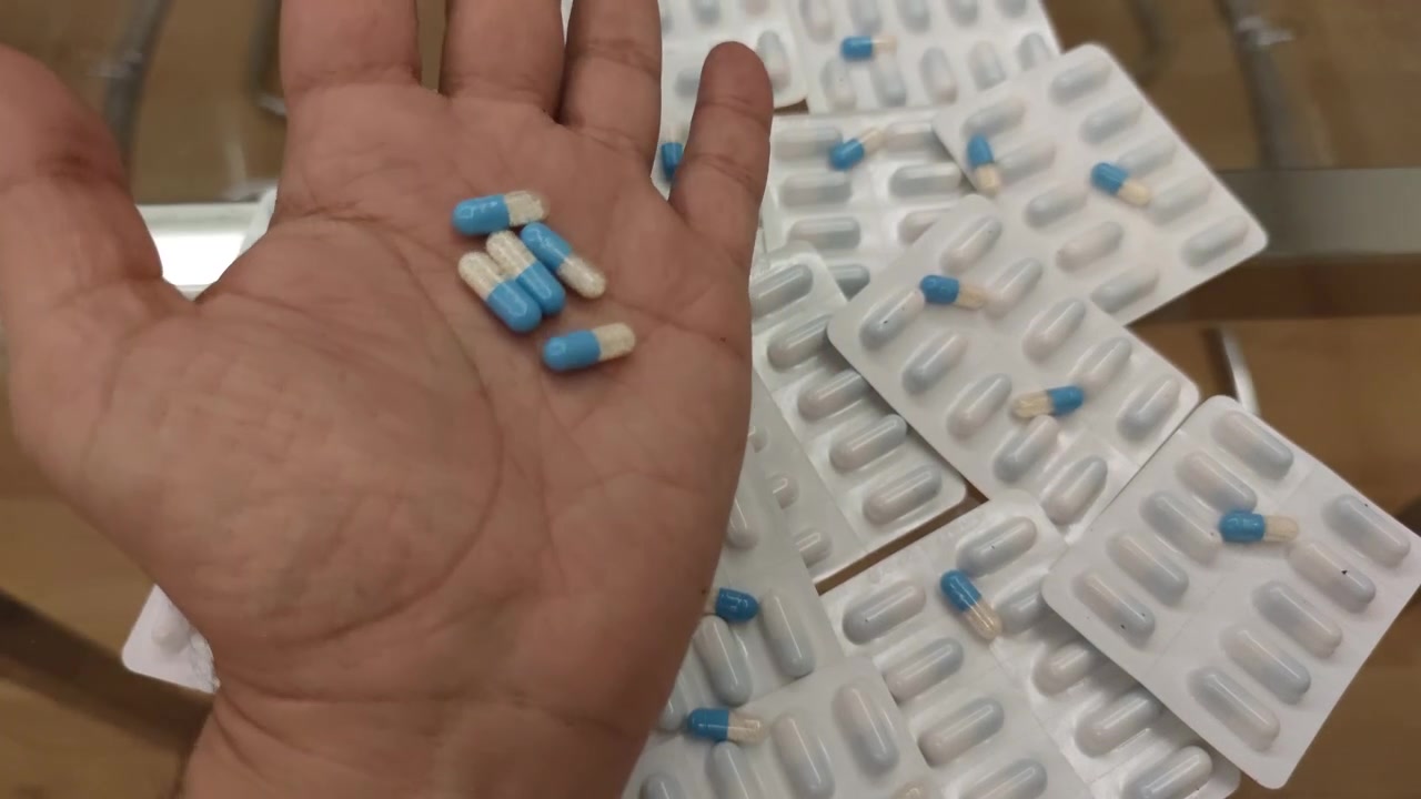 Mano abriéndose para revelar cápsulas azules y blancas