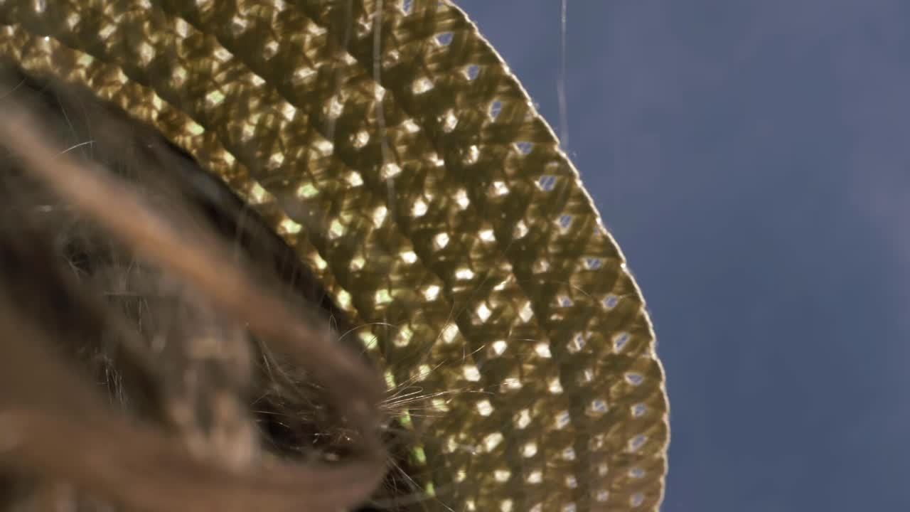 Woman holding onto straw hat on a windy day with hair blowing close up shot