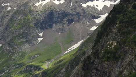 Detail-pan-up-shot-of-a-green-valley-in-the-Alps-unveiling-the-permanent-snow-of-the-glacier-in-ProRes-4K