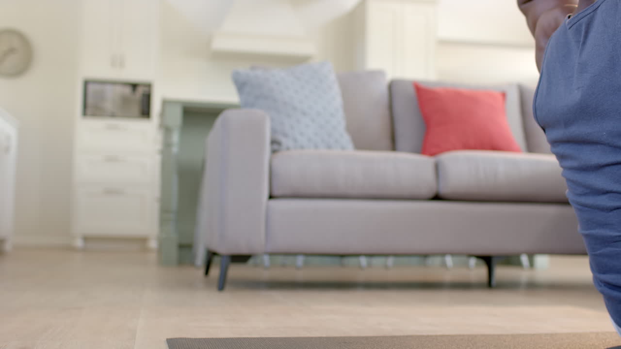 초점을 맞춘 아프리카계 미국인 남자가 이 나는 거실에서 크런치를 하고 있습니다.