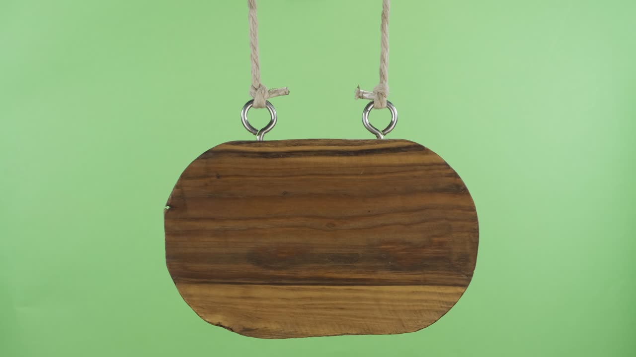 오래된 빈 나무 표지판이 으로 흔들리고 있습니다. 녹색 화면. 표지판