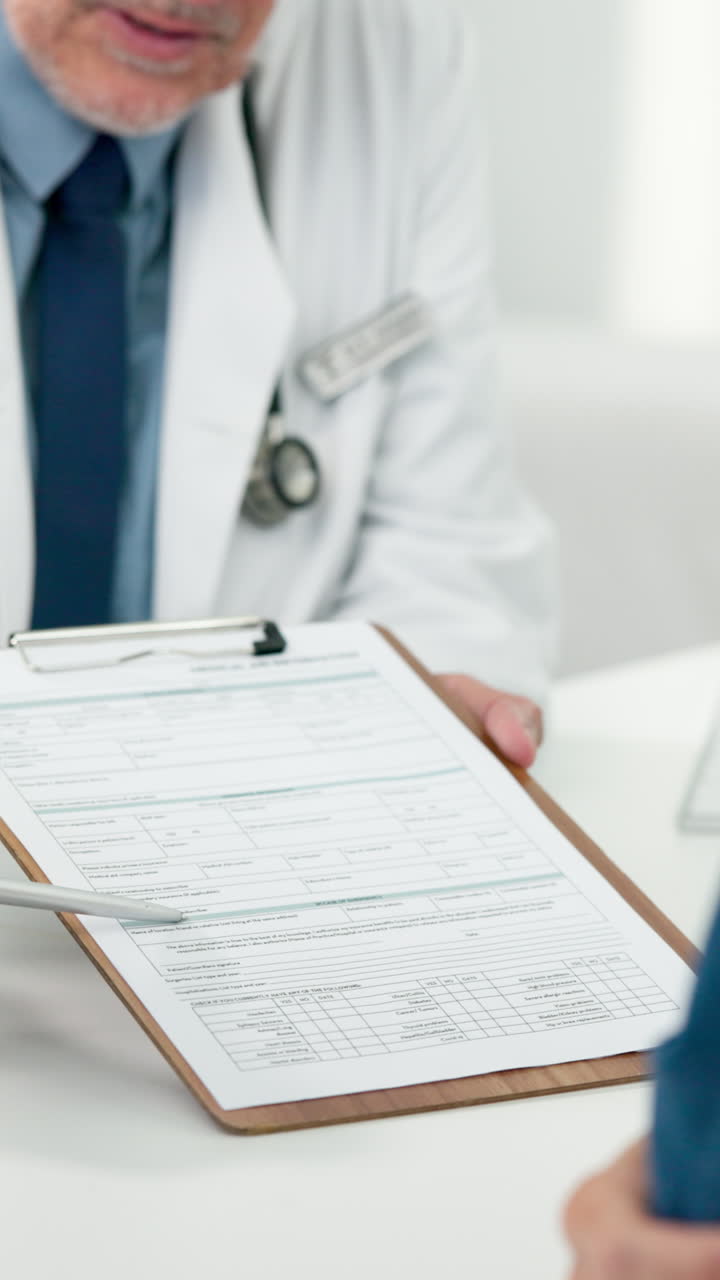 Medico che spiega un modulo medico al paziente durante una consultazione.