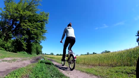young woman riding vintage bicycle along a rural road in a village