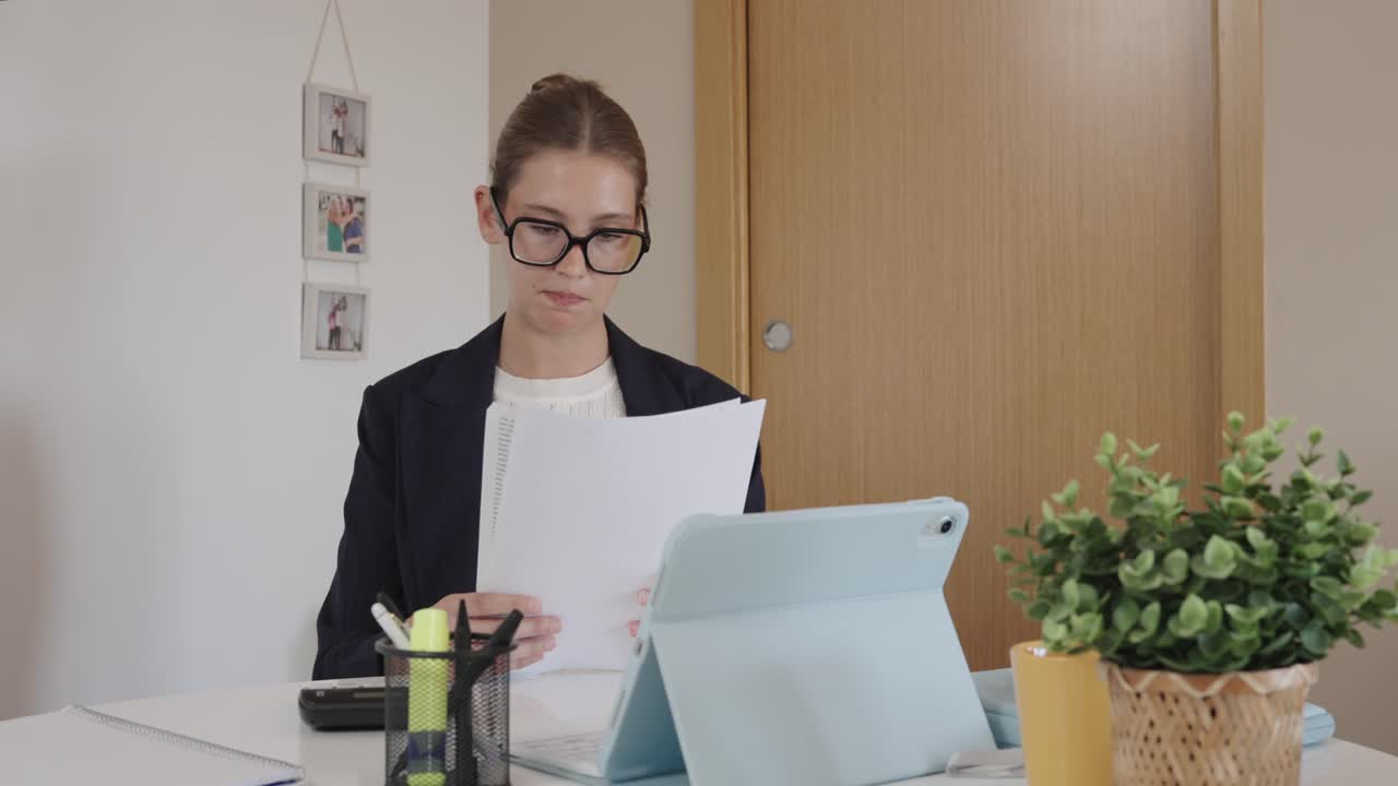 Woman working at desk with tablet and papers