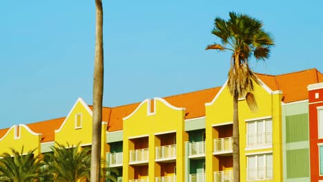 Yellow-Residential-Building-In-Curacao-With-Palm-Trees-In-Front---low-angle-shot