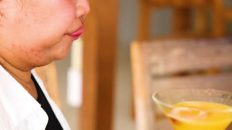 a person savoring a vibrant yellow cocktail in a relaxed setting with warm lighting