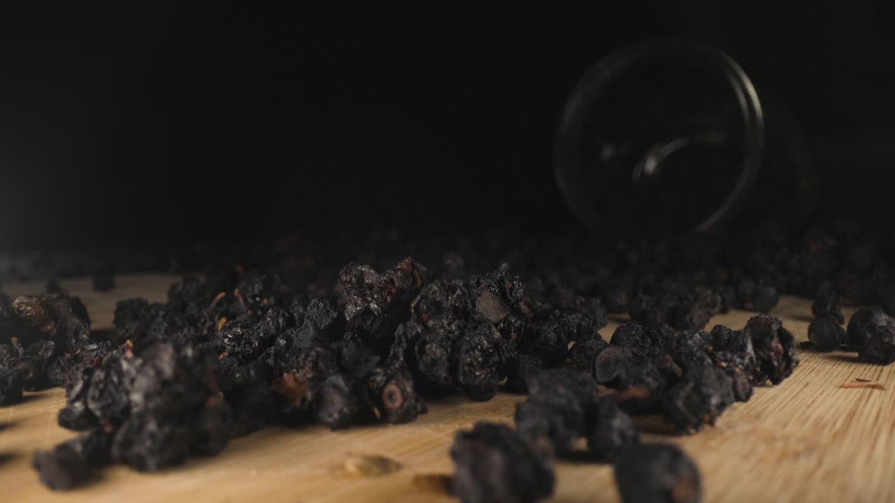 말린 익은 야생 딸기가 떨어지고, 나무 표면에 흩어져 있고, 돌리는 프로브 렌즈 보기를 닫고, 어두운 배경의 유리병