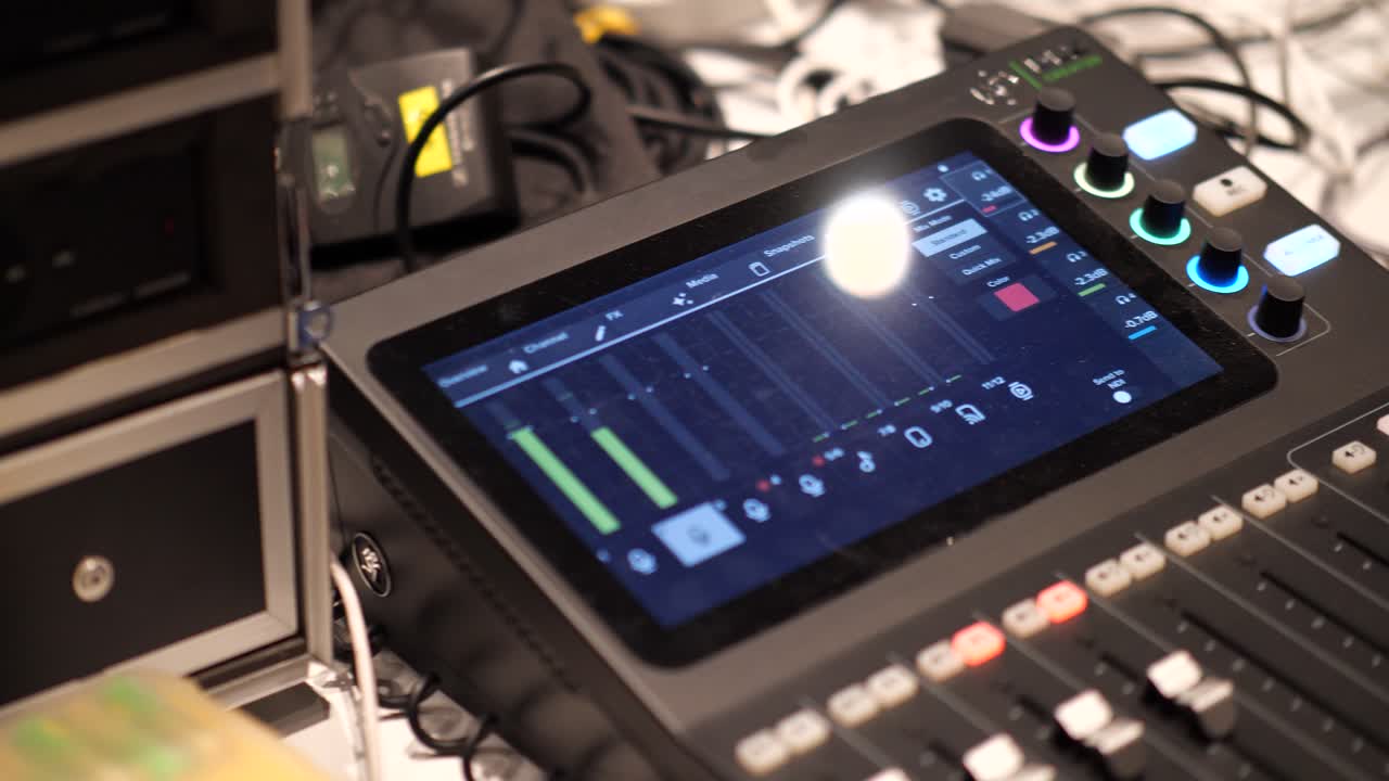 A professional studio with a sound mixing console, knobs, sliders, surrounded by monitors and cables