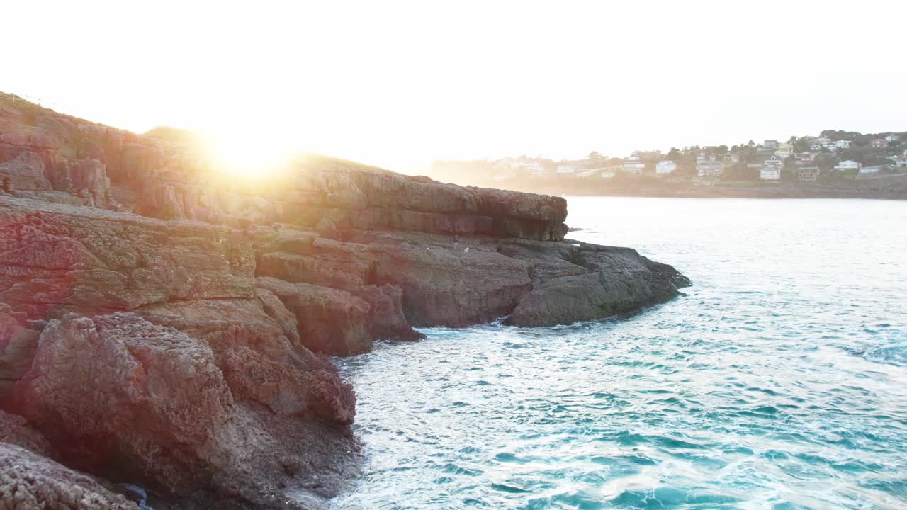 puesta de sol justo encima de las grandes rocas de una isla cerca de cantabria en el golfo de vizcaya donde las olas golpean suavemente las paredes rocosas